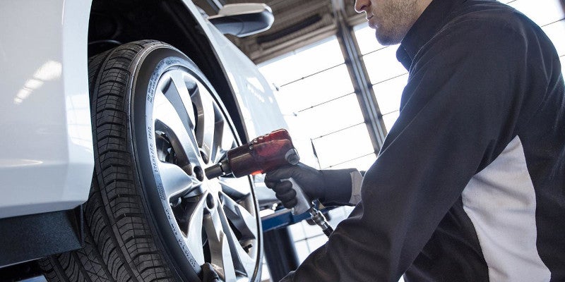 mechanic tightening tire on lifted car